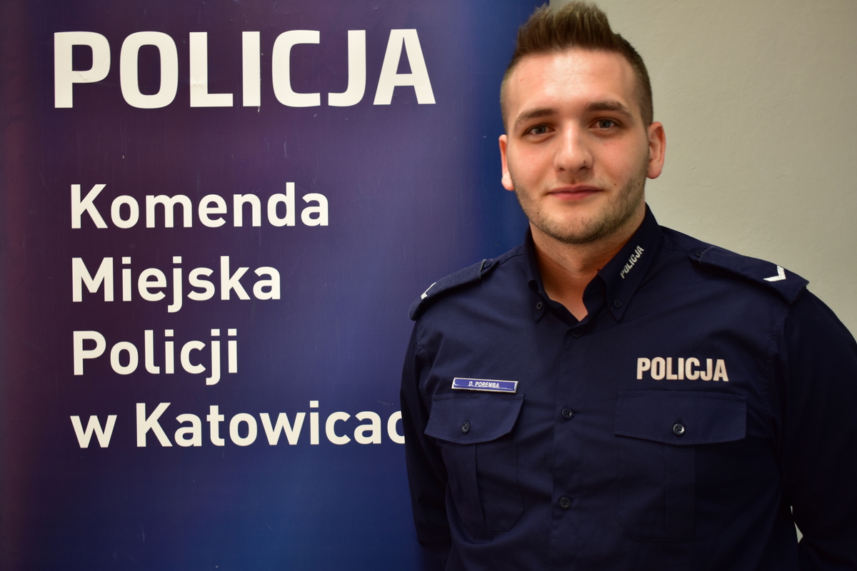 dzielnicowy sierżant Dariusz Poremba stoi przed logo Komendy Miejskiej Policji w Katowicach