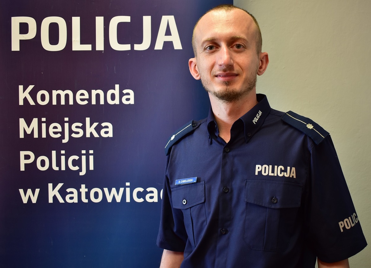 młodszy aspirant bartosz chmielewski - nowy dzielnicowy w Katowicach stoi na tle loga policji w Katowicach