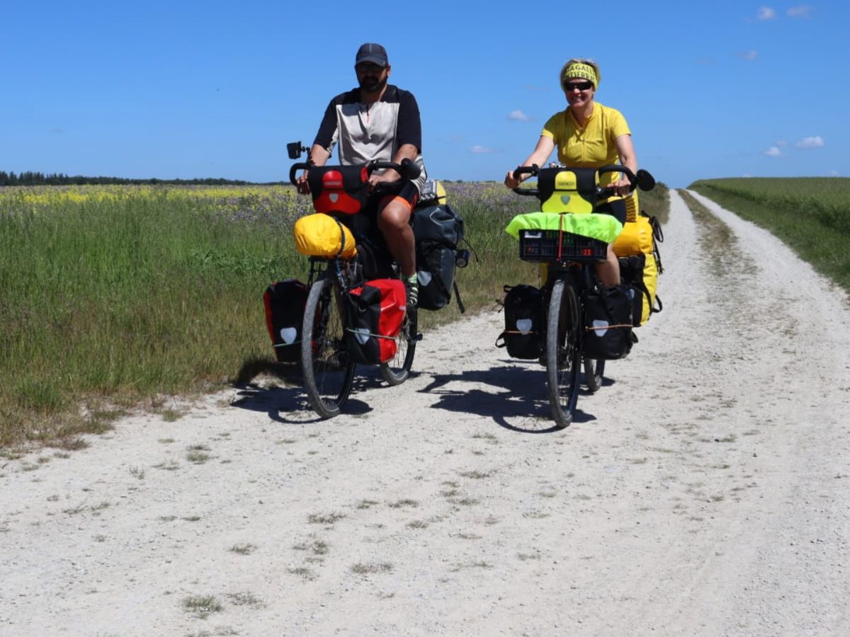 dwie osoby na rowerze z bagażami na polnej drodze