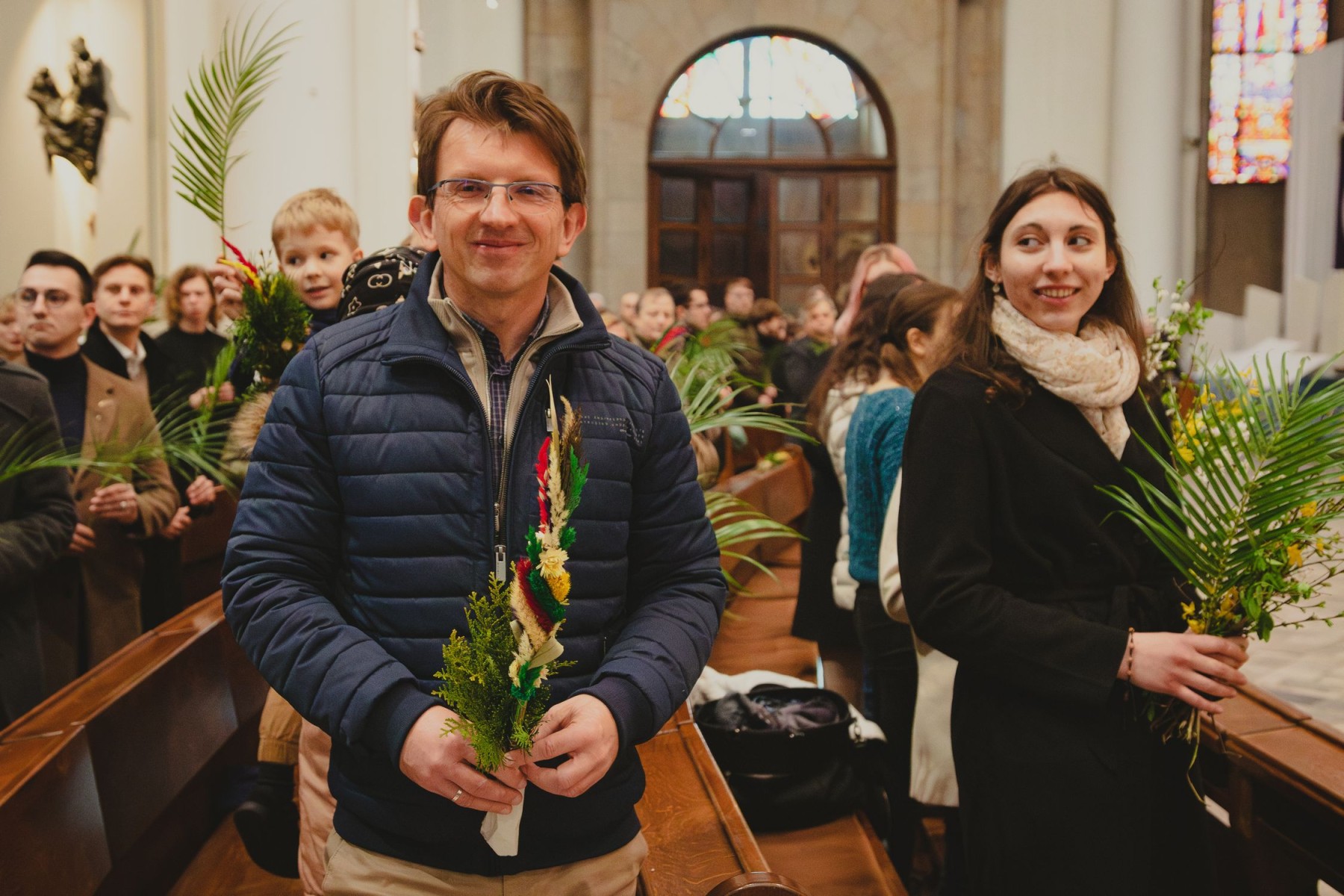 mężczyzna w kurtce w kościele trzyma palmę