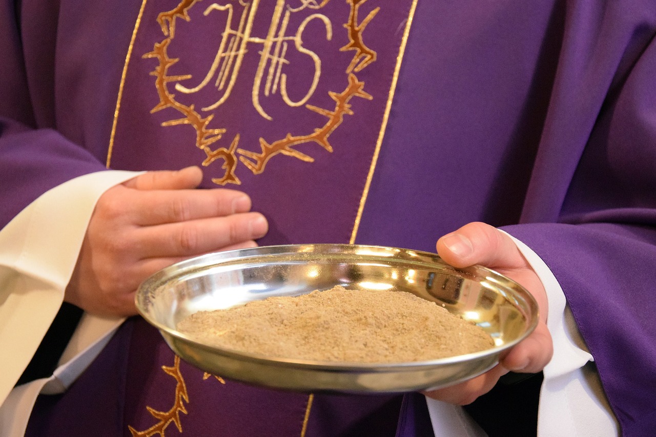 Ksiądz trzyma naczynie z popiołem na Środę Popielcową